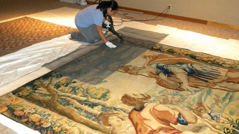 UE student restoring a large tapestry